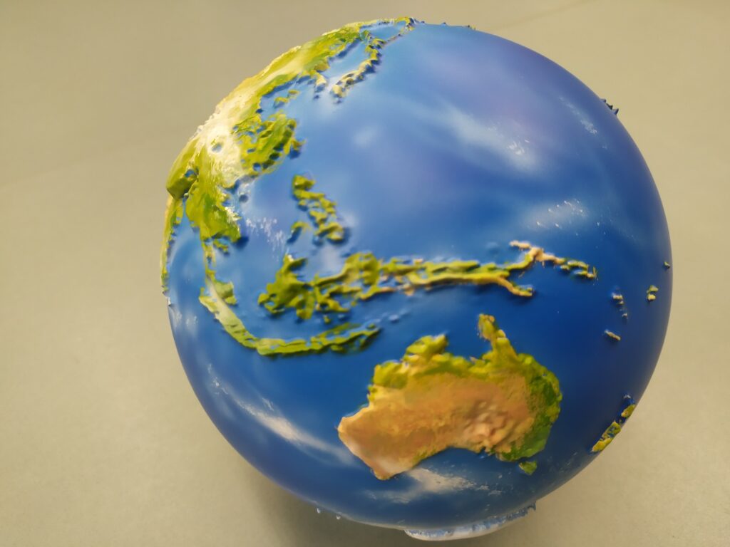 Earth globe on a table. Painted in different colours: blue (sea), brown, green and yellow. Globo de la Tierra sobre una mesa, pintado en varios colores: azul (mar) marrón verde y amarillo.