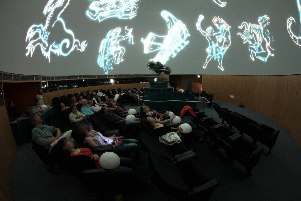 Inside of a planetarium, with people sitting with the tactile half-spheres on their lap / Interior de un planetario con el público sosteniendo la semiesfera en el regazo